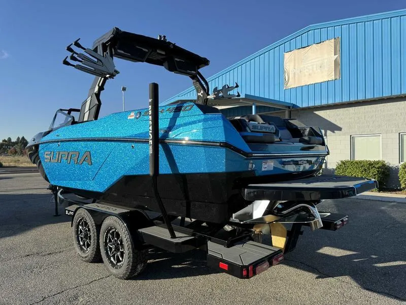Slide: The Image of 2025 Supra SA boat in vibrant blue on a trailer, parked outside a building. - 6