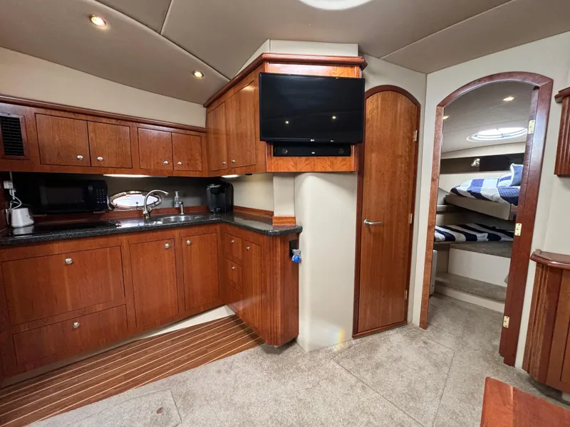 Slide: The Image of 2005 Cruisers Yachts 440 Express interior with kitchen, TV, and cozy sleeping area. - 22