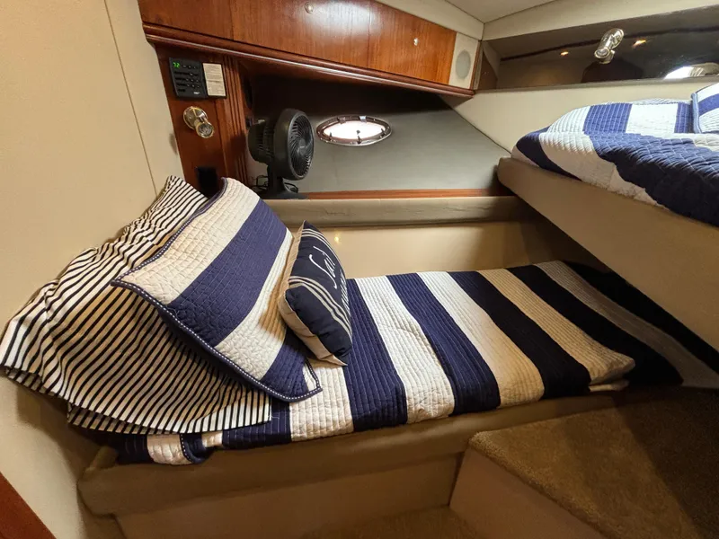 Slide: The Image of 2005 Cruisers Yachts 440 Express cabin with striped bedding and wooden accents. - 30