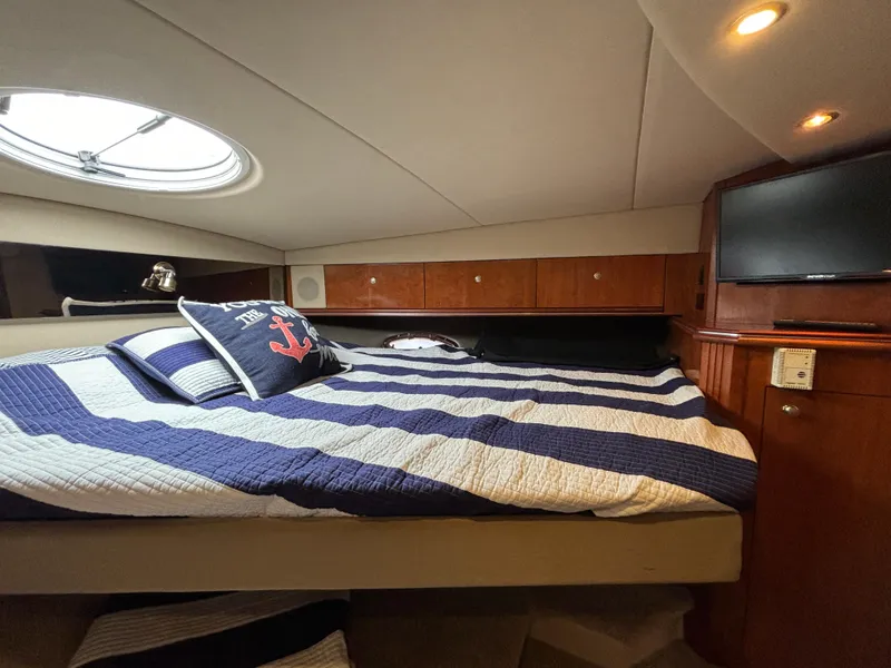 Slide: The Image of Luxurious cabin interior of 2005 Cruisers Yachts 440 Express with striped bedding and porthole. - 32