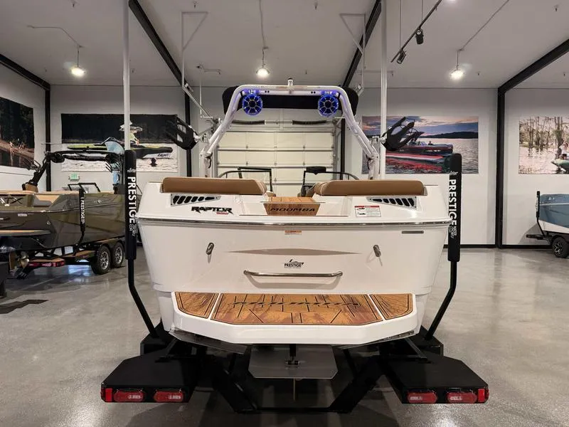 Slide: The Image of 2025 Moomba Mojo boat in showroom, rear view with trailer, modern design. - 19