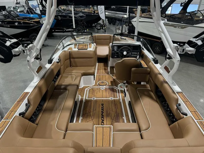 Slide: The Image of 2025 Moomba Mojo boat interior with tan seating and sleek dashboard in showroom. - 3