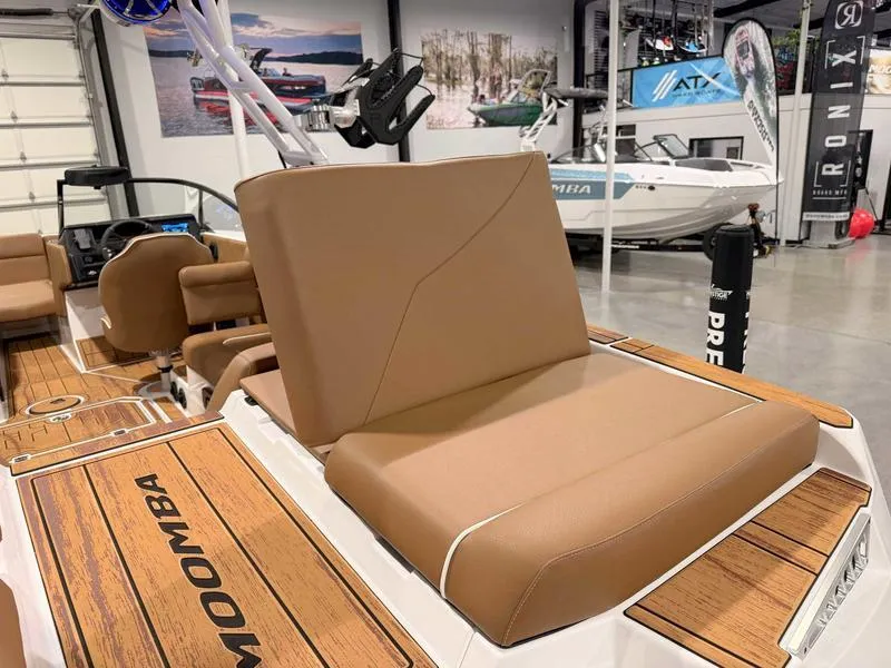 Slide: The Image of 2025 Moomba Mojo boat interior with tan seating and wood accents in showroom. - 4