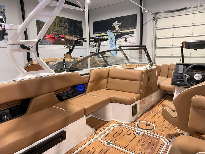 Slide: The Image of 2025 Moomba Mojo boat interior with tan seating and wood accents in a showroom. - 6