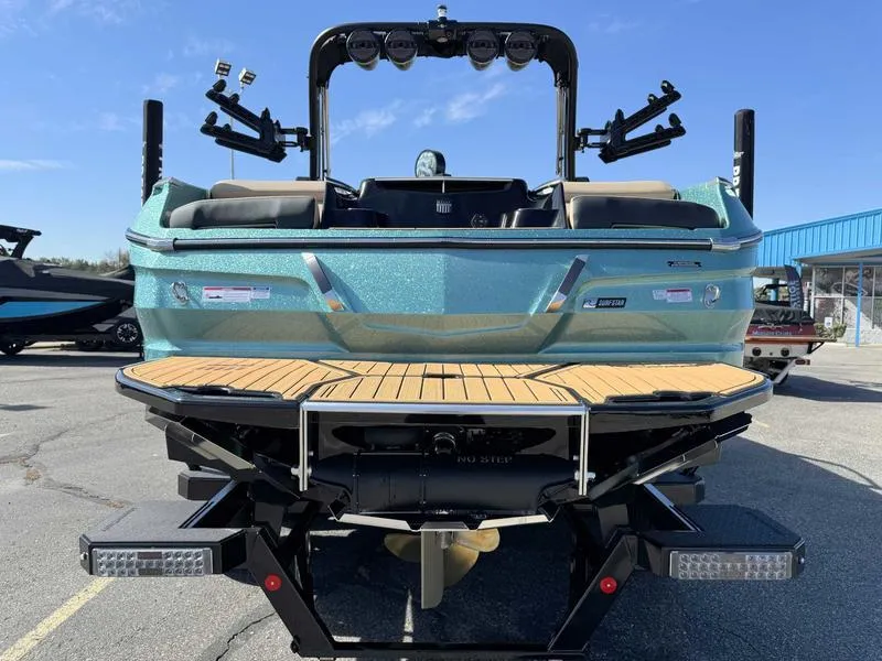 Slide: The Image of 2025 MasterCraft X24 boat, rear view, showcasing deck and seating, parked outdoors. - 7