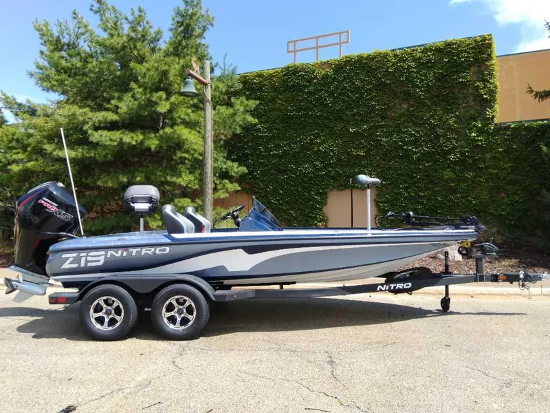 The Image of 2025 Nitro Z19 boat on trailer, parked outdoors, with lush greenery background. - 0