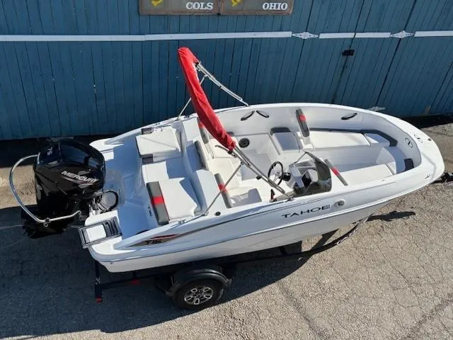 Slide: The Image of 2025 Tahoe T16 boat with red canopy on trailer, parked by blue wall. - 5
