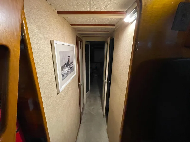 Slide: The Image of Narrow hallway inside a 1951 Chris-Craft Catalina boat, featuring wood paneling and framed artwork. - 11