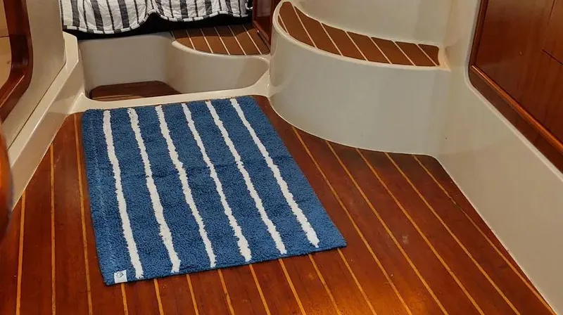 Slide: The Image of Interior of 2006 Grady-White Express 360 with wooden flooring and blue striped rug. - 21