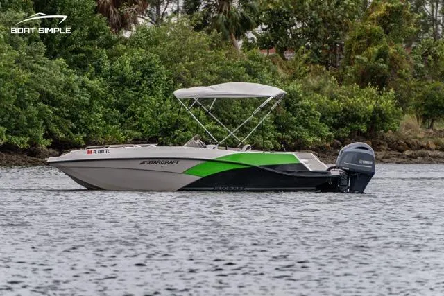Slide: The Image of 2023 Starcraft SVX 231 OB DH boat on water, green and black design, with canopy. - 2