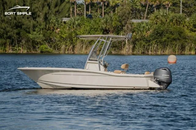 Slide: The Image of 2022 Scout 195 Sportfish boat on a calm lake with lush greenery background. - 0