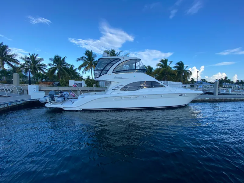 Slide: The Image of 2007 Sea Ray 52 Sedan Bridge yacht docked by palm trees under blue sky. - 14