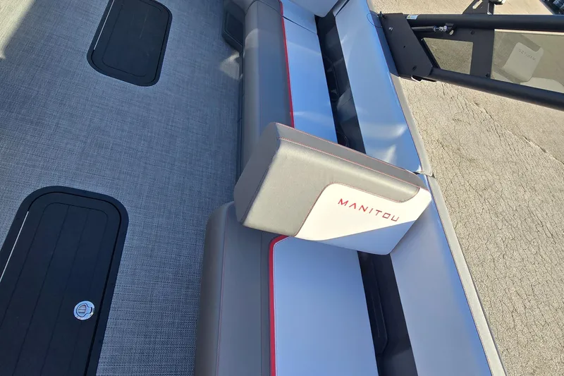 Slide: The Image of 2025 Manitou 240 Cruise boat interior with gray seating and red accents. - 7