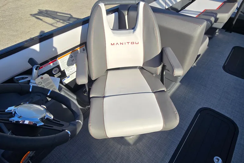 Slide: The Image of 2025 Manitou 240 Cruise boat interior with steering wheel and comfortable seating. - 8