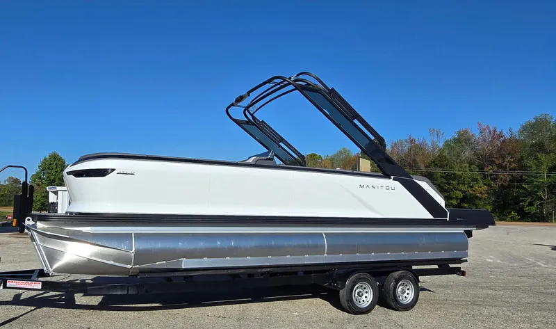 Slide: The Image of 2025 Manitou 240 Cruise pontoon boat on trailer under clear blue sky. - 9
