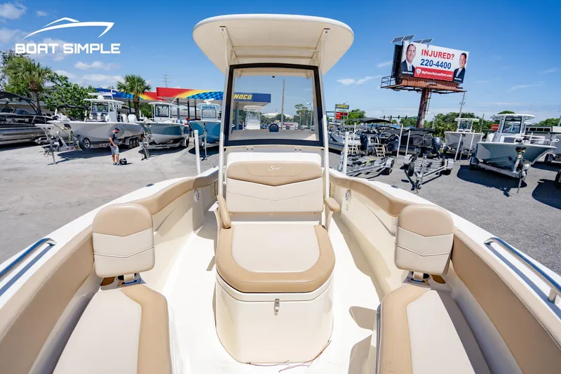Slide: The Image of 2023 Scout 215 XSF boat interior with tan seating, displayed at a dealership. - 6