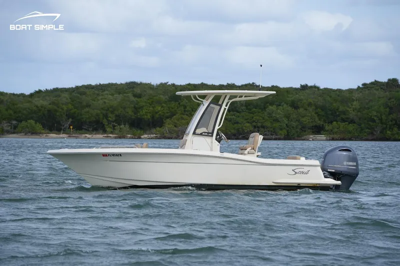 Slide: The Image of 2023 Scout 215 XSF boat on water, side view with trees in background. - 2