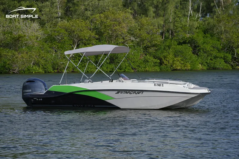 Slide: The Image of 2023 Starcraft SVX 191 OB boat on a calm river with lush greenery. - 1