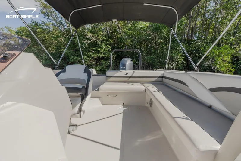 Slide: The Image of 2023 Starcraft SVX 211 OB boat interior with seating and canopy, surrounded by greenery. - 7