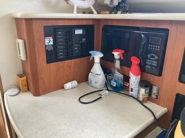 Slide: The Image of 2004 Bayliner 3055 Ciera interior with microwave and cleaning supplies on counter. - 12
