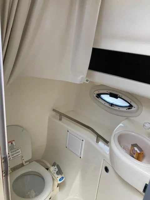 Slide: The Image of 2004 Bayliner 3055 Ciera boat bathroom with toilet, sink, and porthole window. - 14