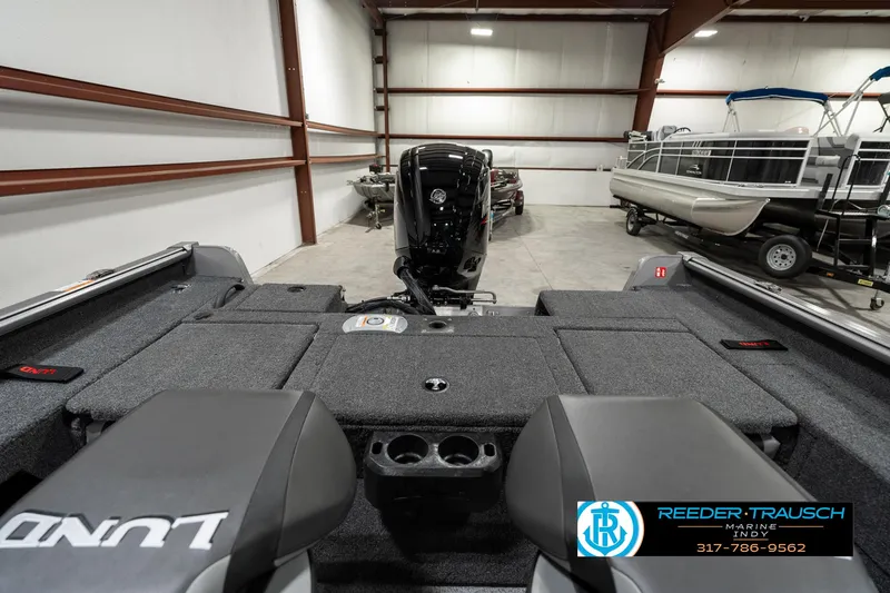 Slide: The Image of 2025 Lund 1775 Impact XS boat interior in showroom with motor and seating. - 15