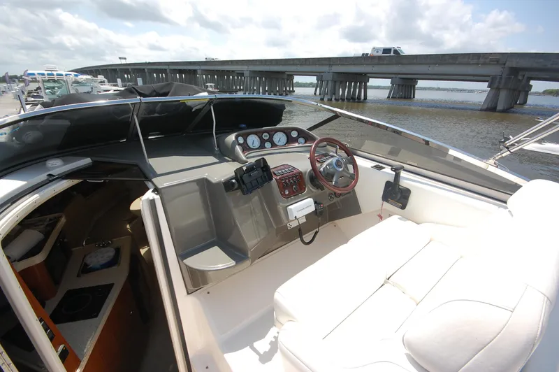 Slide: The Image of 2007 Regal 2665 Commodore boat interior with steering wheel and dashboard, docked near a bridge. - 7