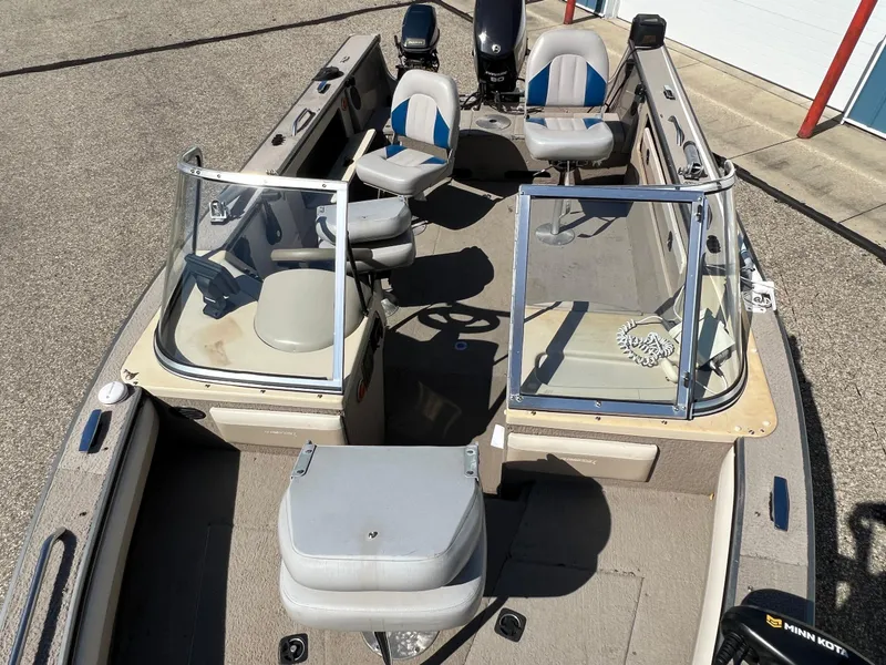 Slide: The Image of 2001 Alumacraft Trophy 175 boat with seating and steering console, parked on pavement. - 18