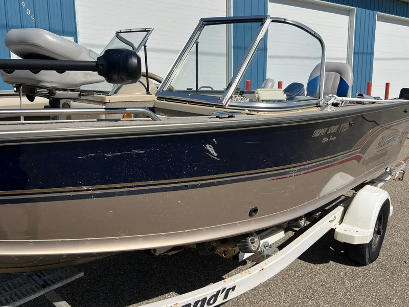 Slide: The Image of 2001 Alumacraft Trophy 175 boat on trailer, parked outside blue building. - 22