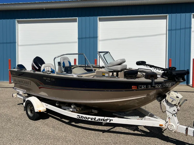 Slide: The Image of 2001 Alumacraft Trophy 175 boat on ShoreLand'r trailer, parked outside blue building. - 3