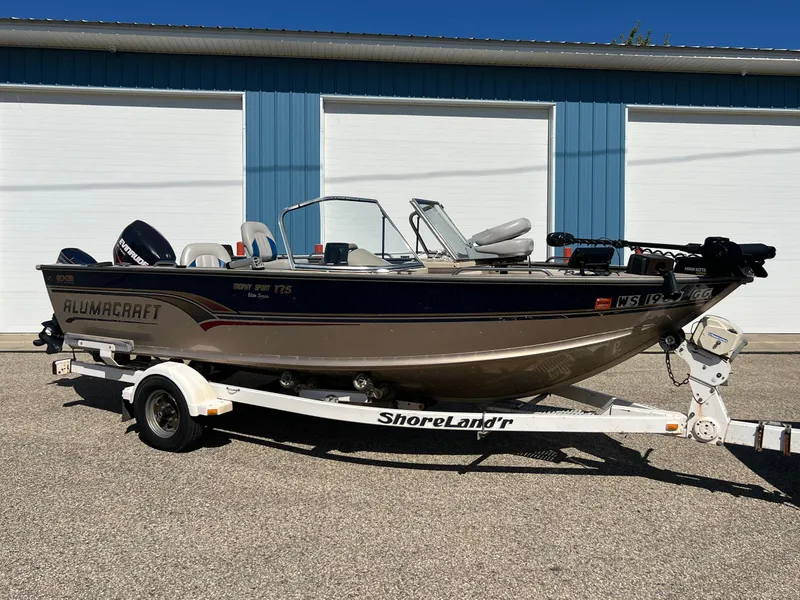 Slide: The Image of 2001 Alumacraft Trophy 175 boat on ShoreLand'r trailer, parked outside blue building. - 7