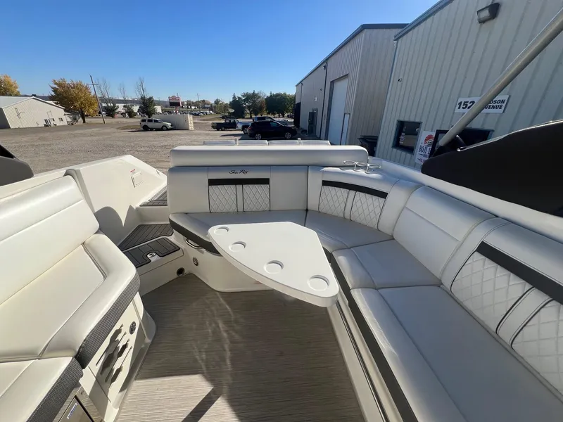 Slide: The Image of 2018 Sea Ray 280 SLX boat interior with white seating and table, parked near industrial buildings. - 31