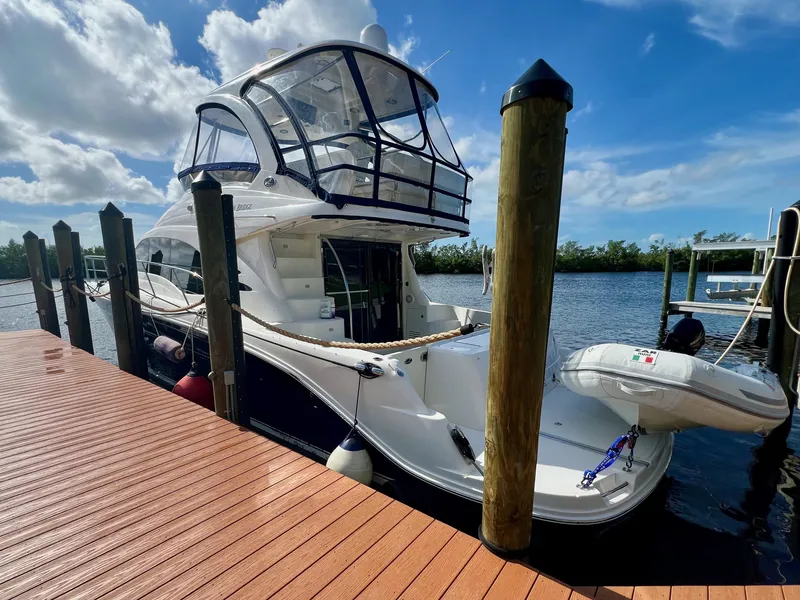Slide: The Image of 2007 Sea Ray 52 Sedan Bridge yacht docked by wooden pier under blue sky. - 4