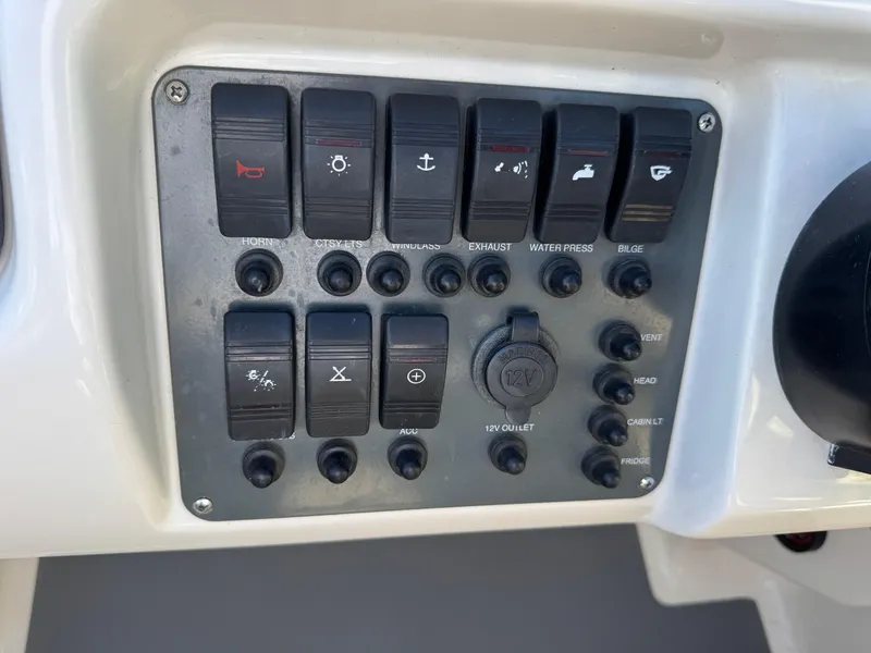 Slide: The Image of Control panel of a 2005 Chris-Craft Corsair 28 boat with various switches and buttons. - 12