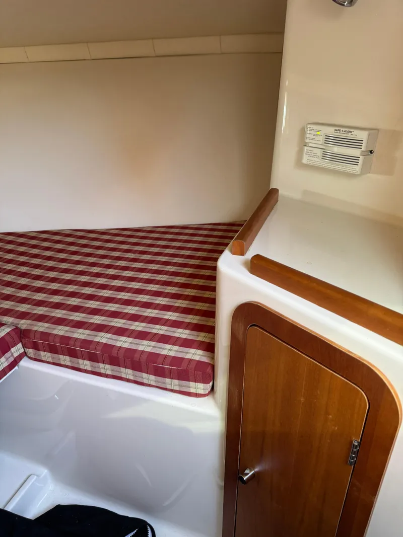 Slide: The Image of 2005 Chris-Craft Corsair 28 cabin interior with plaid bedding and wooden cabinet. - 17