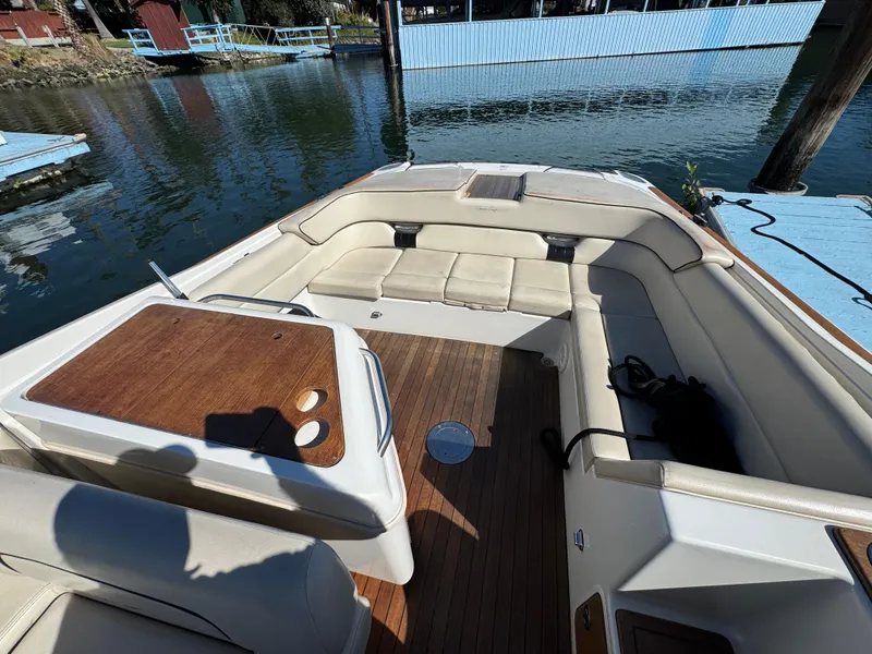 Slide: The Image of 2005 Chris-Craft Corsair 28 boat interior with beige seating and wooden deck. - 19
