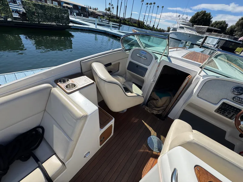 Slide: The Image of 2005 Chris-Craft Corsair 28 boat interior with white seating and wooden deck. - 20