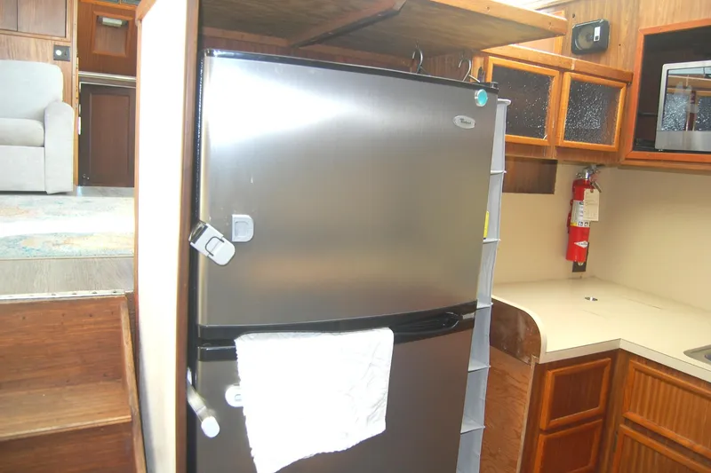 Slide: The Image of Interior of 1981 Hatteras 48 Cockpit MY with stainless steel fridge and wooden cabinetry. - 16