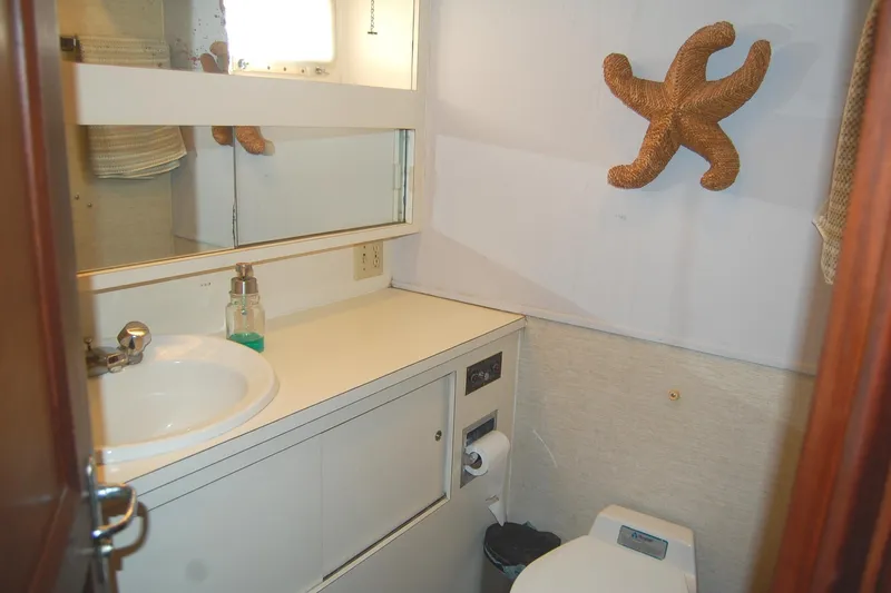 Slide: The Image of 1981 Hatteras 48 Cockpit MY bathroom with sink, mirror, and starfish decor. - 27