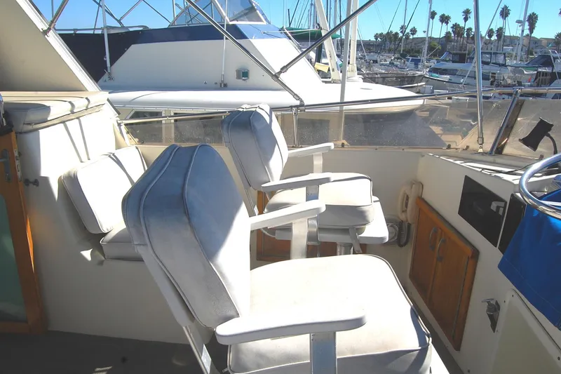 Slide: The Image of 1981 Hatteras 48 Cockpit MY yacht interior with white captain chairs and marina view. - 39