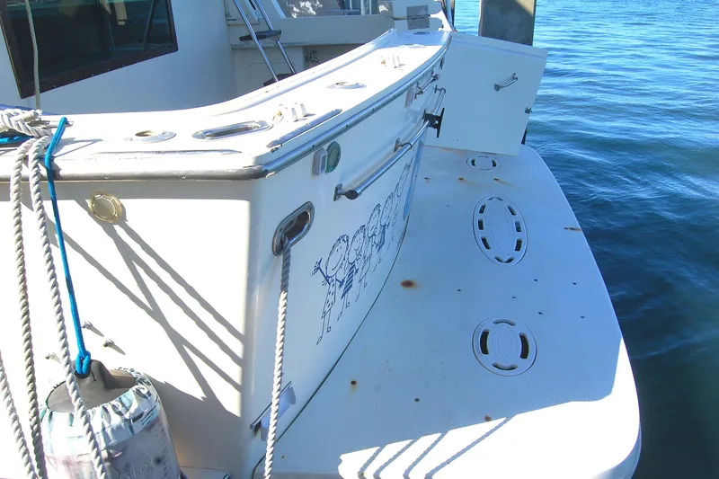 Slide: The Image of 1981 Hatteras 48 Cockpit MY yacht stern view with ropes and water backdrop. - 45