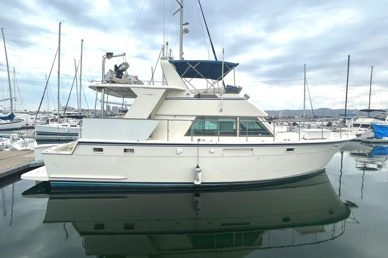 The Image of 1981 Hatteras 48 Cockpit MY yacht docked in a marina, reflecting on calm water. - 0