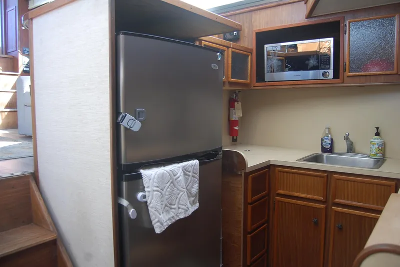 Slide: The Image of 1981 Hatteras 48 Cockpit MY kitchen with stainless steel fridge, microwave, and wooden cabinets. - 17