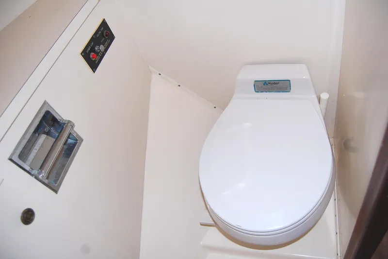 Slide: The Image of 1981 Hatteras 48 Cockpit MY yacht bathroom with white toilet and control panel. - 29