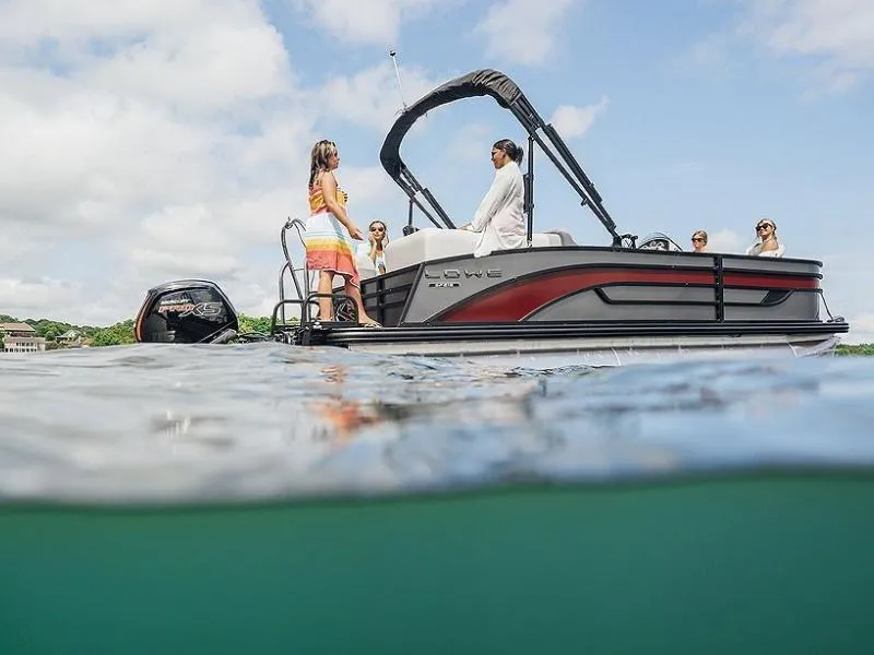 Slide: The Image of 2023 Lowe SF212 Walk-Through pontoon boat on water with people enjoying a sunny day. - 32