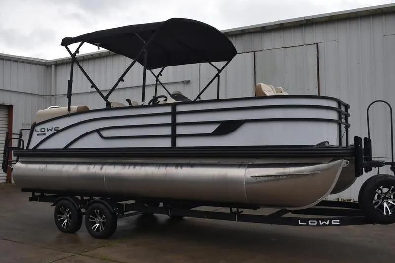 Slide: The Image of 2023 Lowe SF212 Walk-Through pontoon boat with canopy on trailer, parked outdoors. - 4