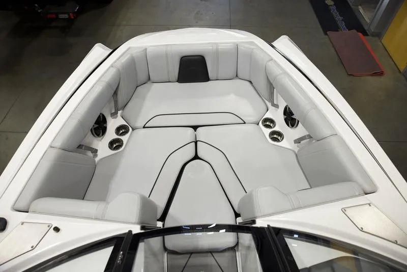 Slide: The Image of 2021 Malibu 21 MLX boat interior with white cushioned seating and built-in speakers. - 14