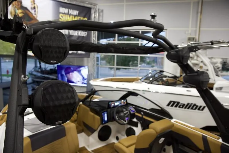 Slide: The Image of 2025 Malibu 22 MXZ boat interior with speakers and dashboard in showroom. - 12