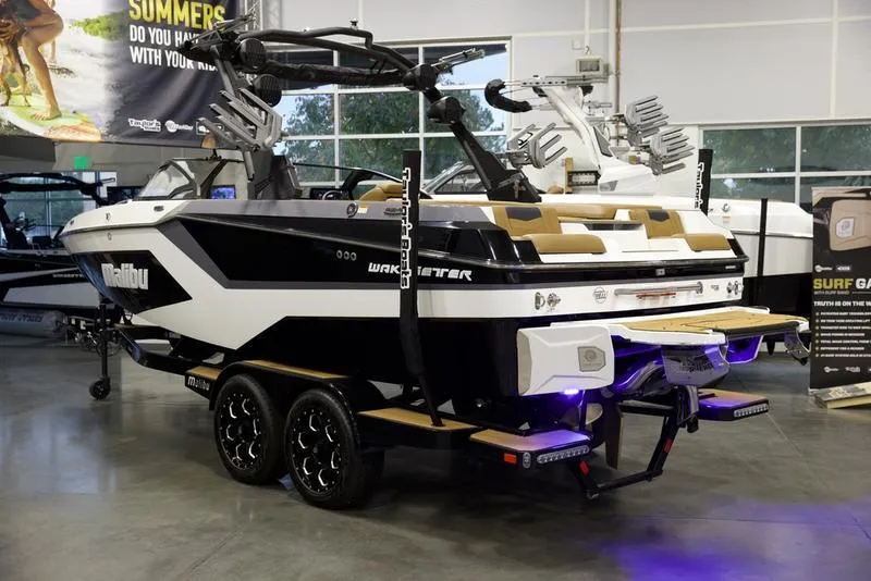 Slide: The Image of 2025 Malibu 22 MXZ boat in showroom, black and white design, on trailer. - 4