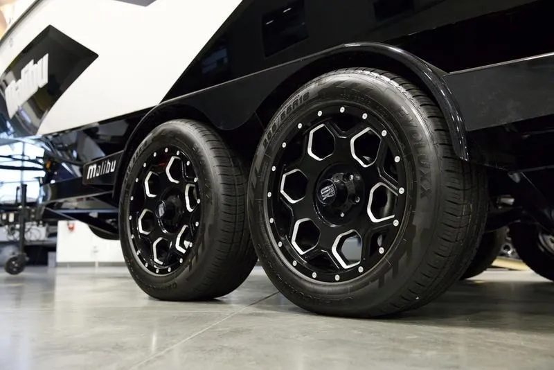 Slide: The Image of 2025 Malibu 22 MXZ trailer with stylish black wheels in a showroom. - 7
